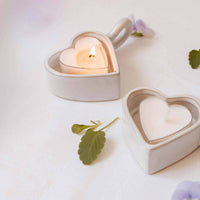 Heart-shaped ceramic candle holders with candles on a light background