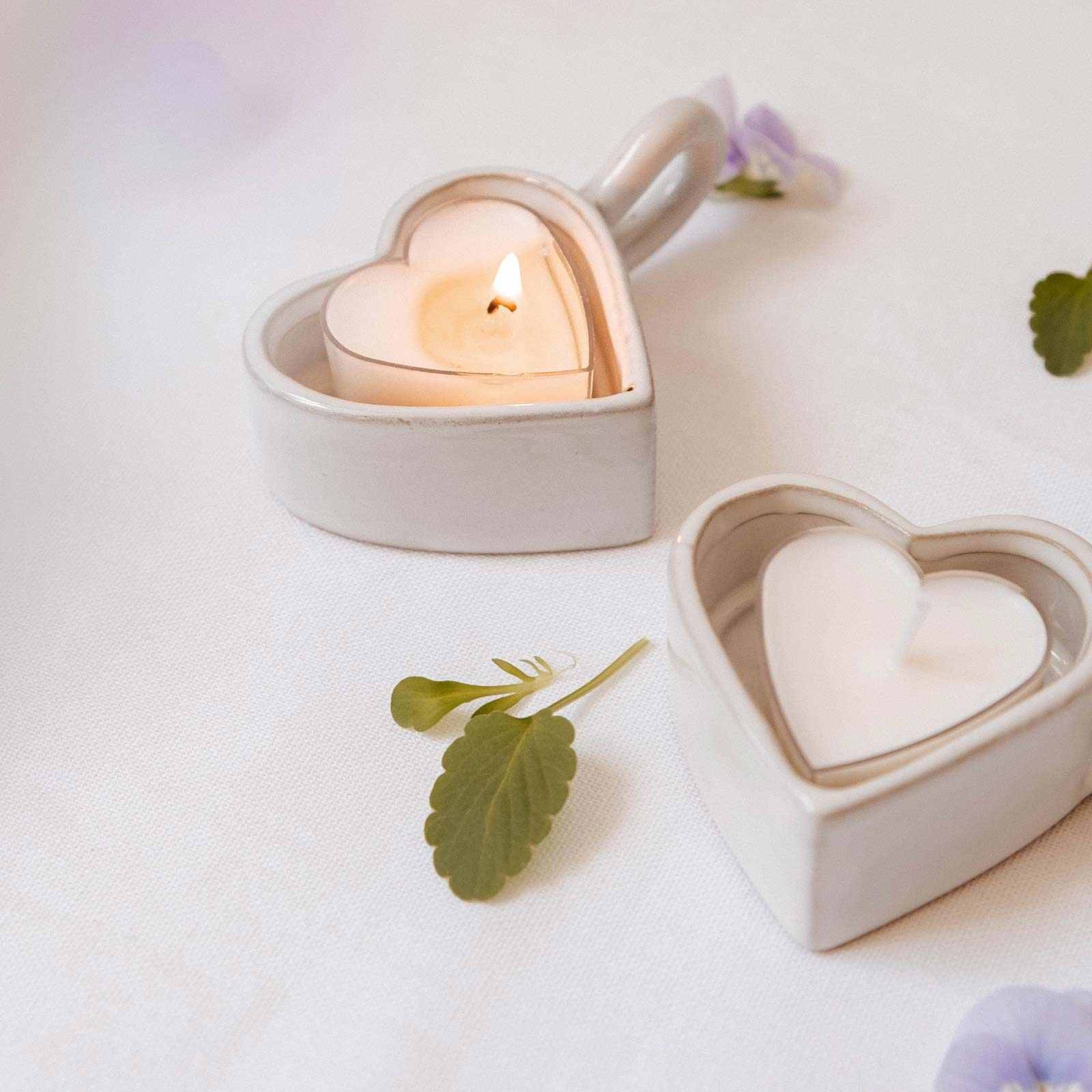 Heart-shaped ceramic candle holders with candles on a light background