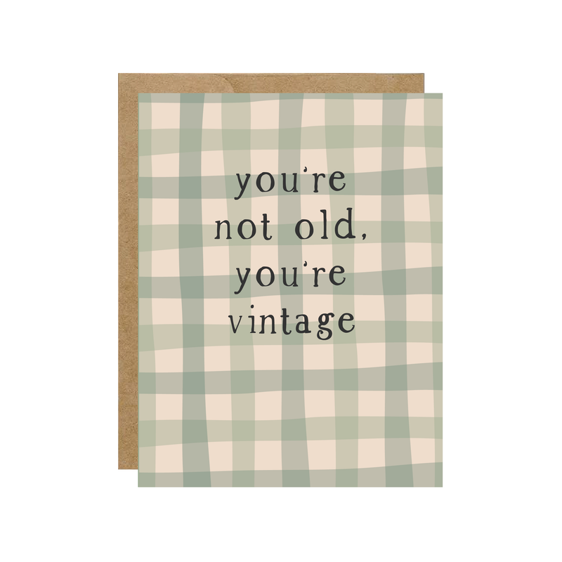 Greeting card with green and beige checkered pattern and text 'you're not old, you're vintage' on a white background.