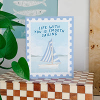 Card with sailboat illustration and 'Life with you is smooth sailing' text on a checkered surface.