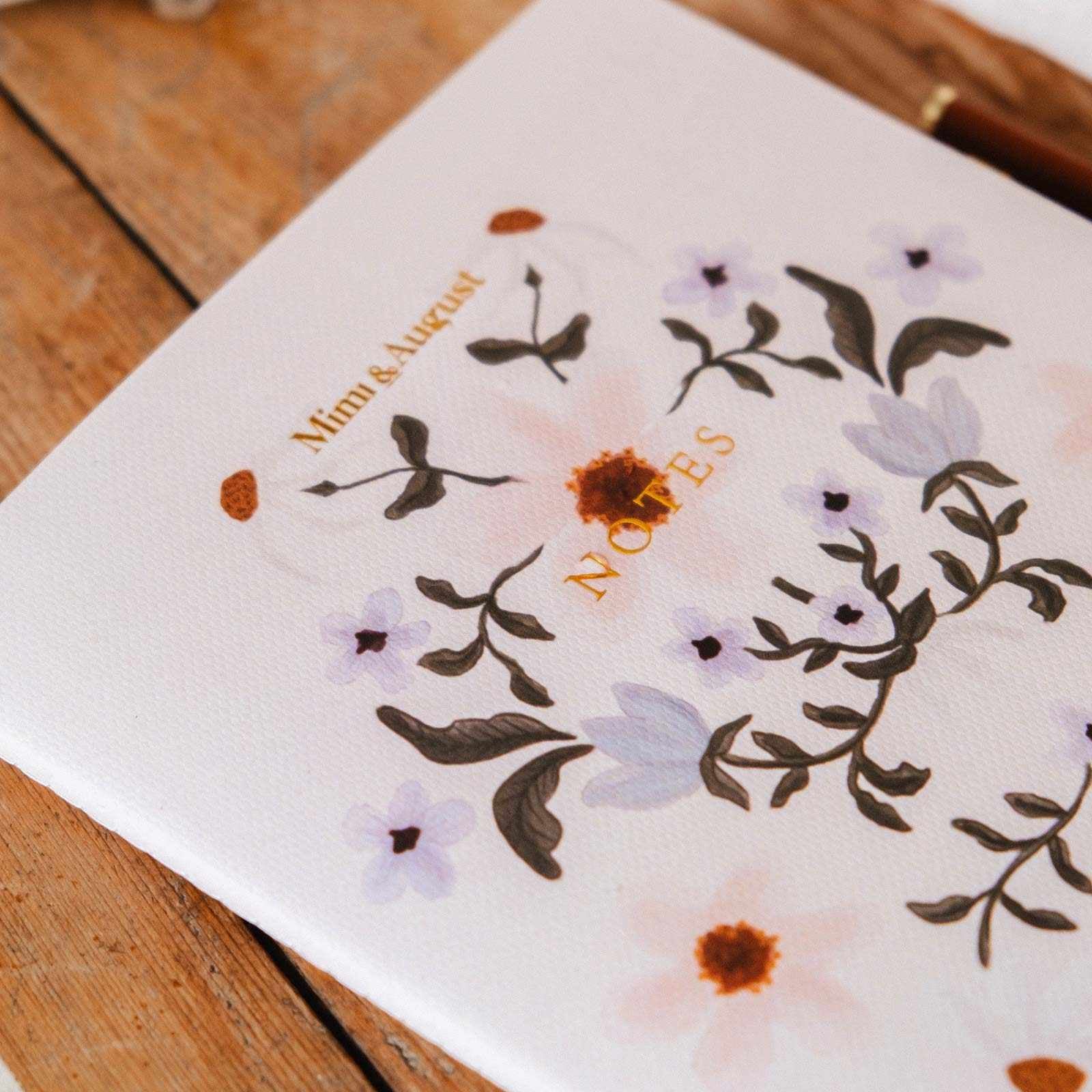 Notebook with floral design and 'Notes' text on a wooden surface