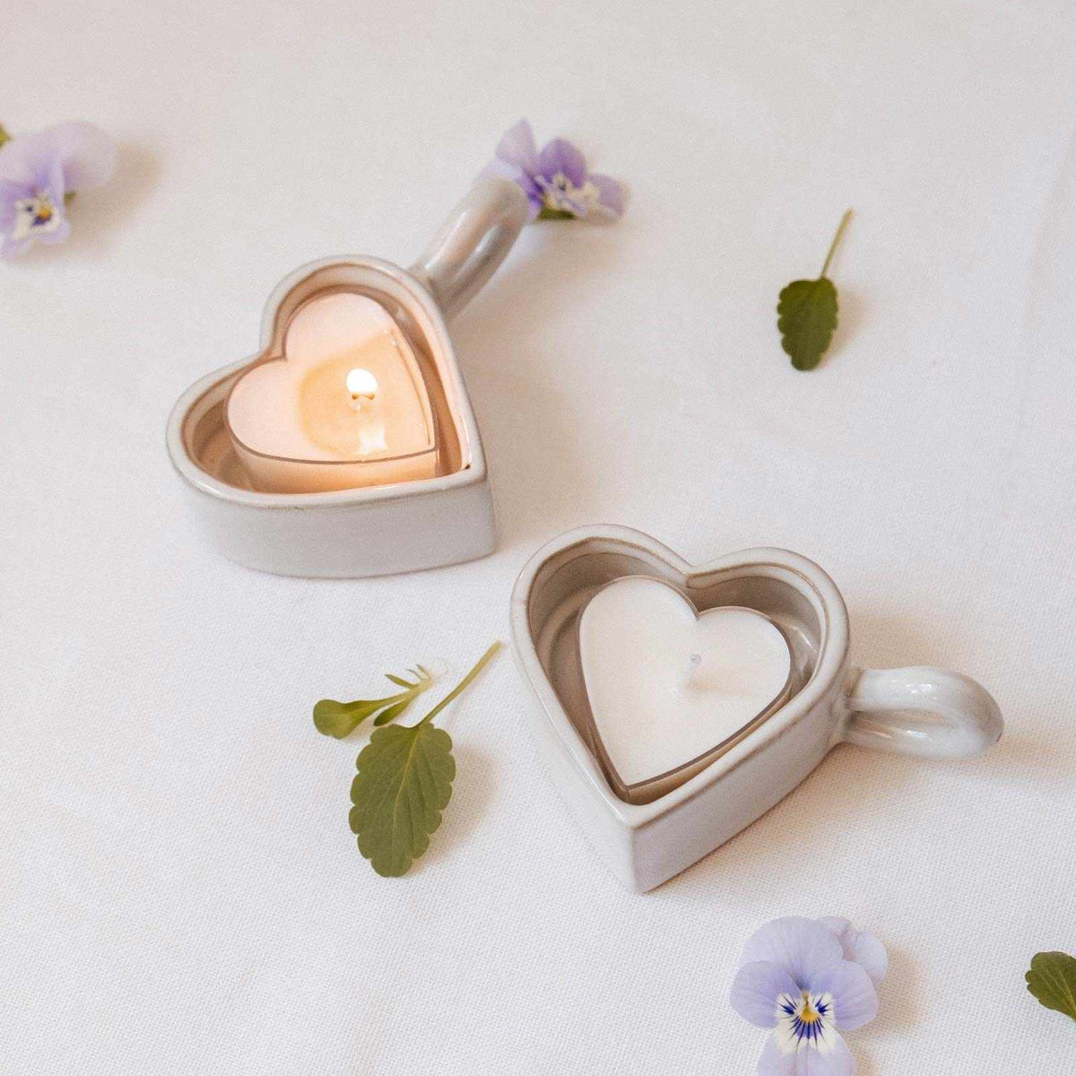 Heart-shaped candle holders with candles on a white background