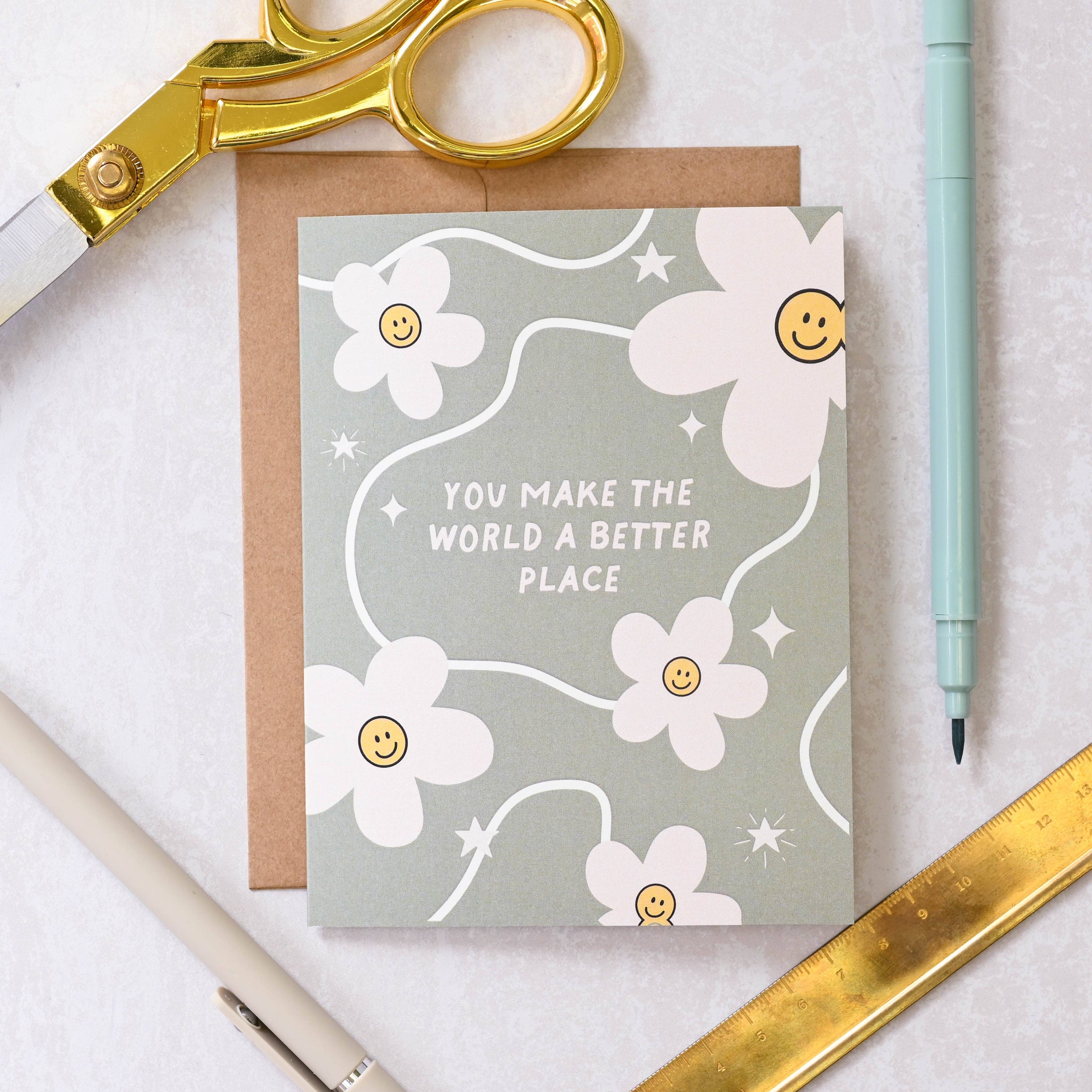 Greeting card with floral design and text on a white surface with stationery items.