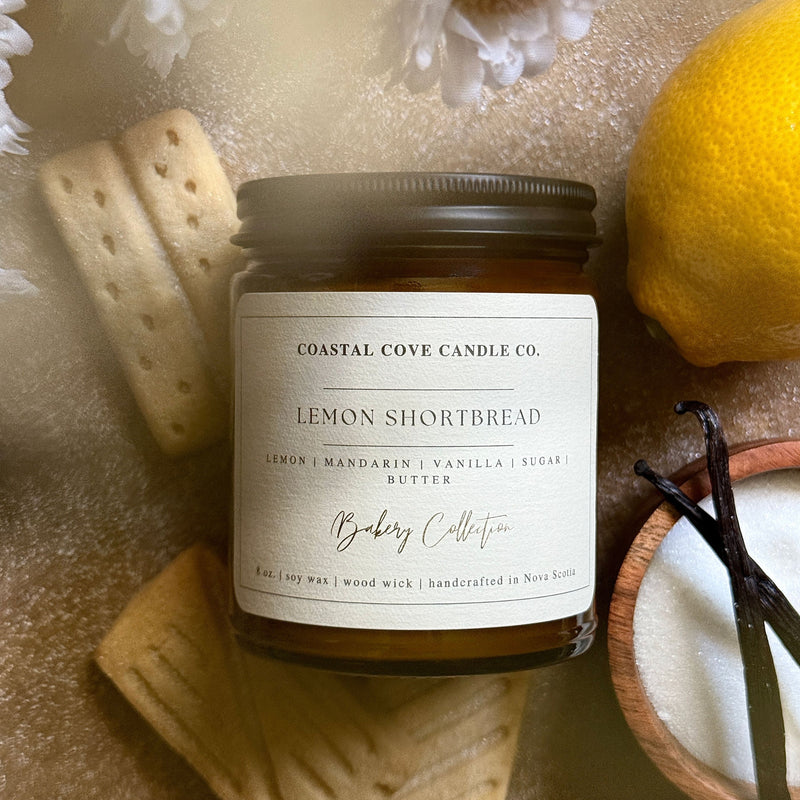 Coastal Cove Candle Co. Lemon Shortbread candle with cookies and a lemon on a textured surface