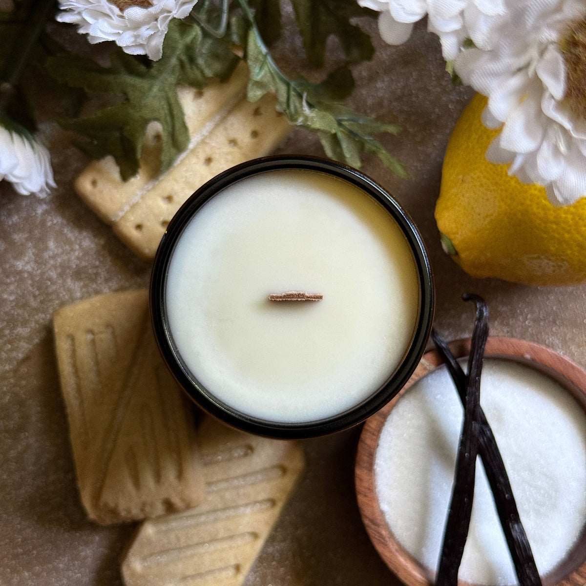 Coastal Cove Candle Co. Lemon Shortbread candle with cookies and a lemon on a textured surface
