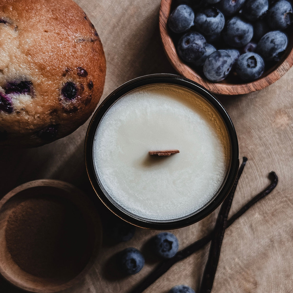 Coastal Cove Candle Co. Blueberry Muffin candle with natural elements on a textured surface