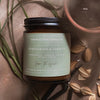 Coastal Cove Candle Co. candle with lemongrass & verbena scent on a textured surface with leaves and seeds.