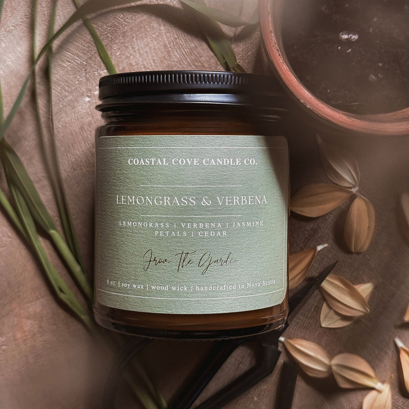 Coastal Cove Candle Co. candle with lemongrass & verbena scent on a textured surface with leaves and seeds.