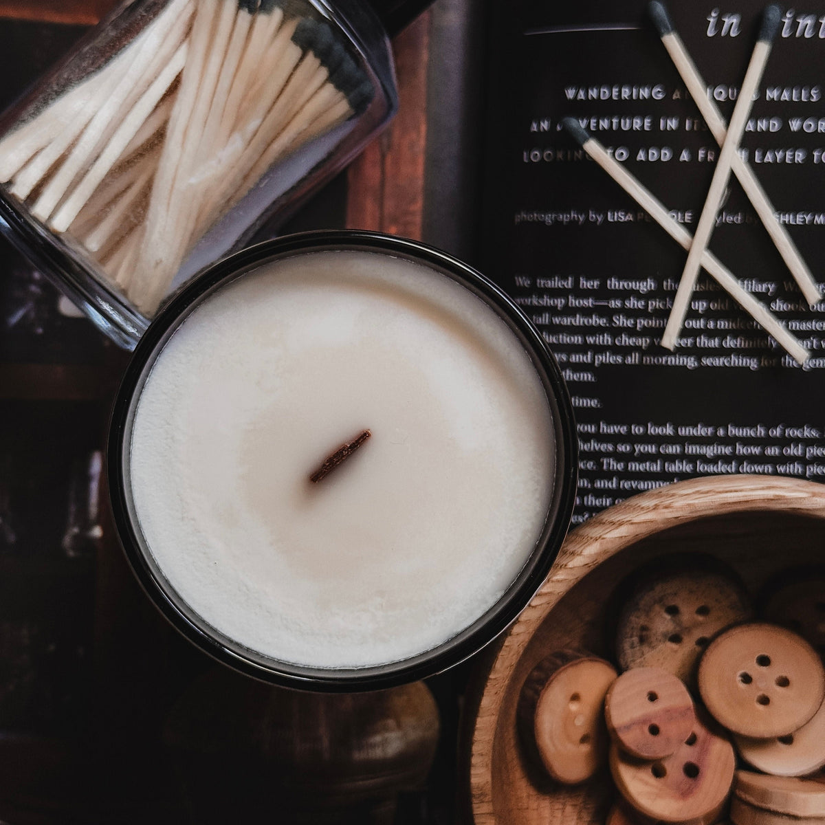 Candle with matches and wooden buttons on a textured surface