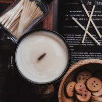 Candle with matches and wooden buttons on a textured surface