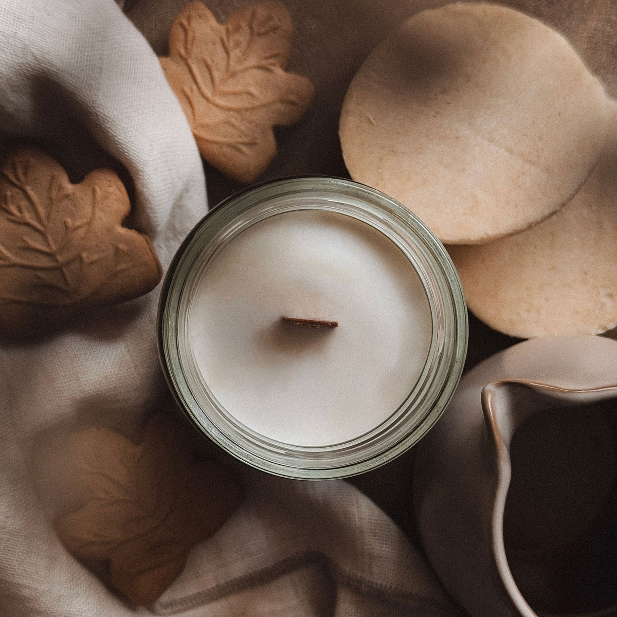 Candle with cookies and a teapot on a textured surface