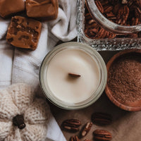 Candle with pecans and fudge on a textured surface