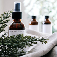 Three bottles of Coastal Cove Candle Co. product on a textured surface with greenery.