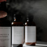 Room spray bottles with labels on a reflective surface