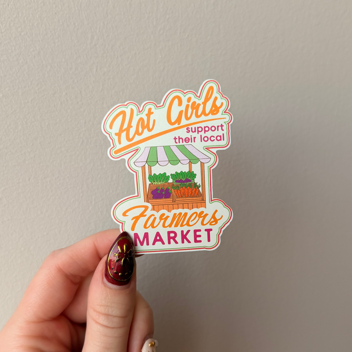 Hand holding a sticker with text and graphics on a plain background