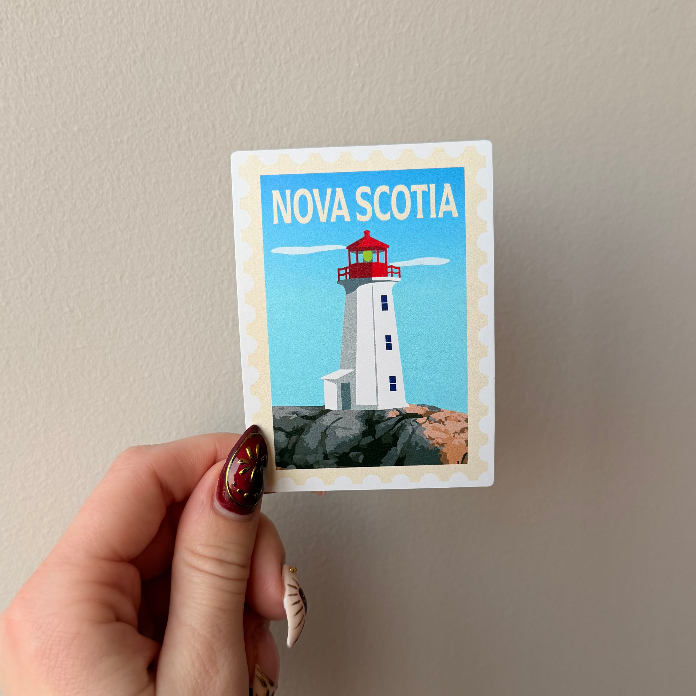 Hand holding a Nova Scotia lighthouse postcard against a plain background