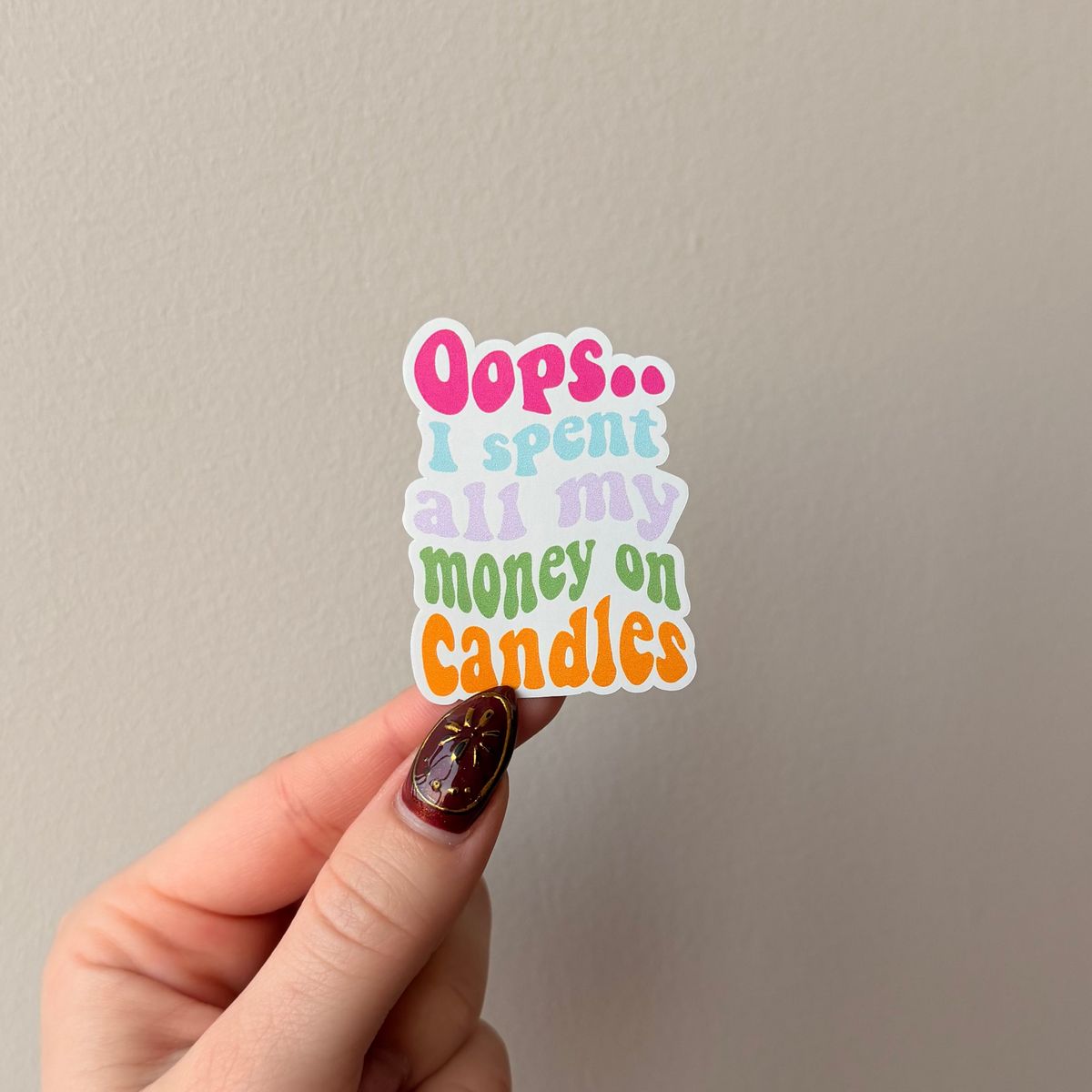 Hand holding a colorful sticker with text against a plain background