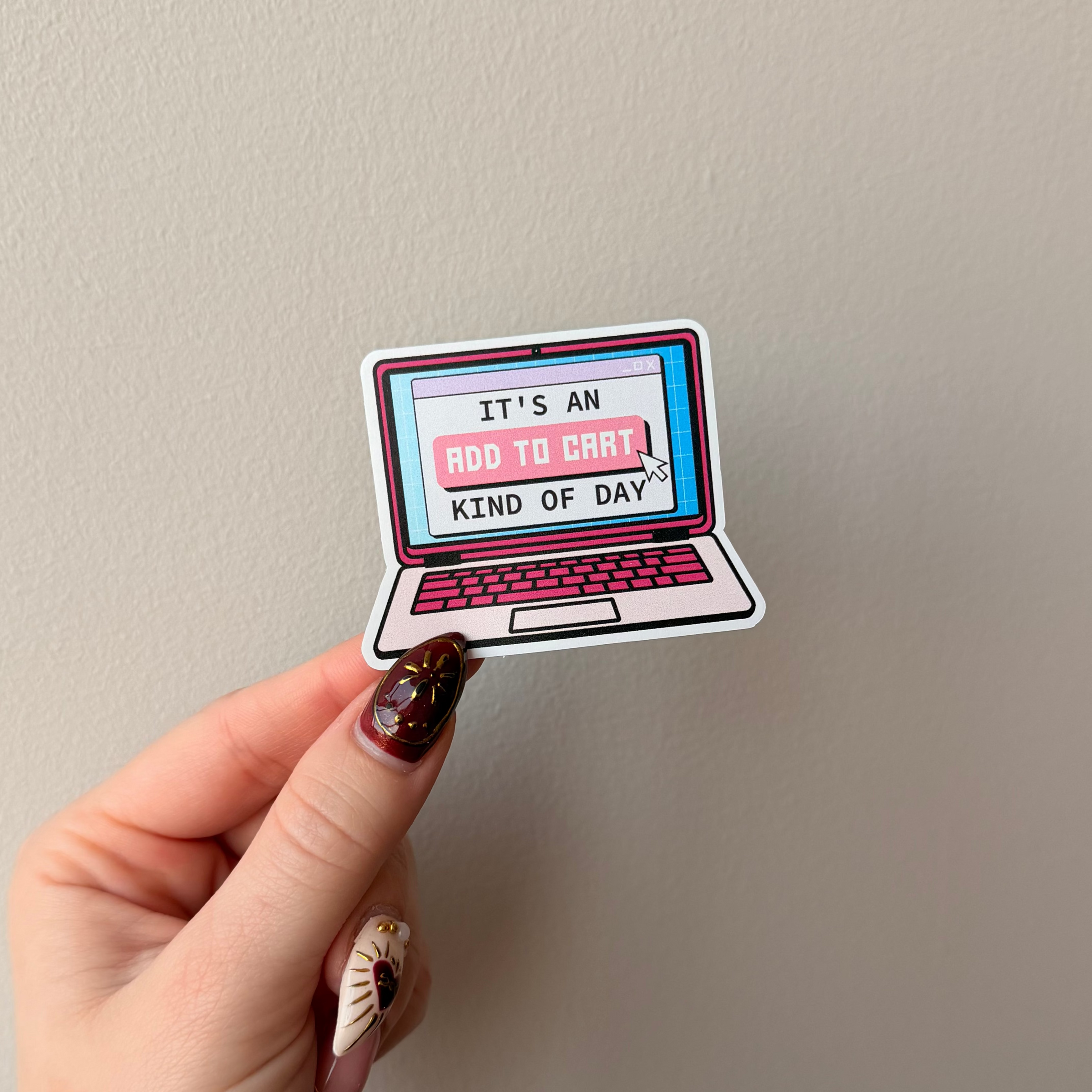 Hand holding a laptop-shaped sticker with text on a plain background