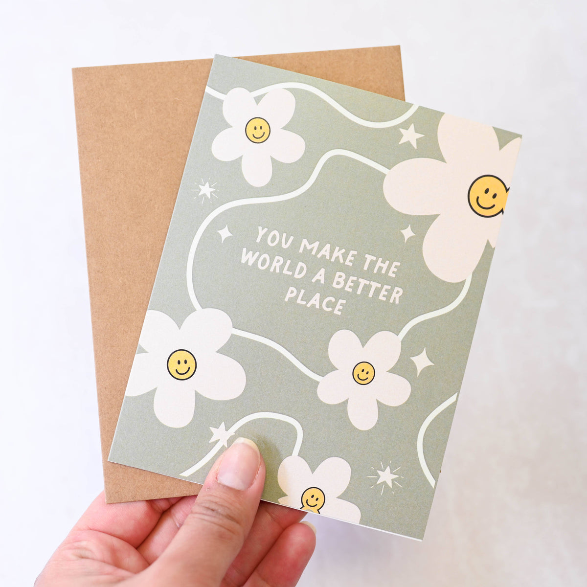 Card with floral design and text held by a hand on a light background