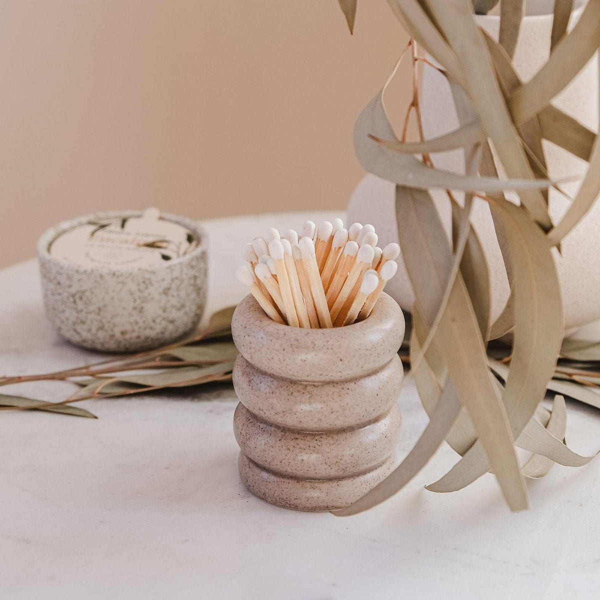 Stack of stone-like containers with toothpicks on a neutral background