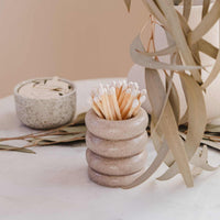 Stack of stone-like containers with toothpicks on a neutral background