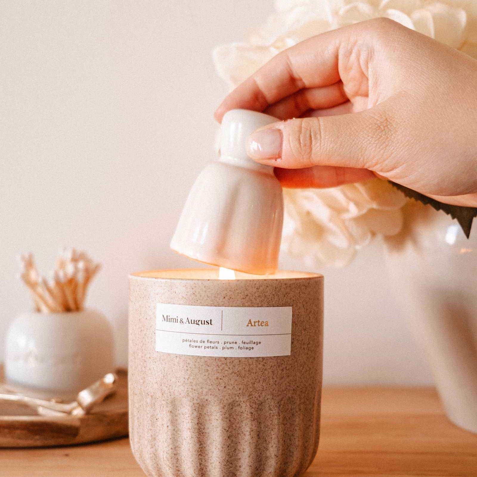 Hand lighting a candle with a decorative label on a wooden surface