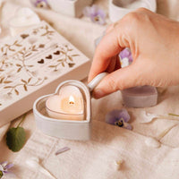 Heart-shaped candle being lit on a soft surface with decorative elements