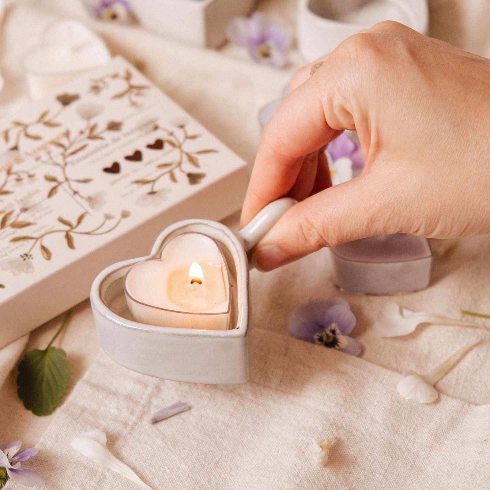 Heart-shaped candle being lit on a soft surface with decorative elements