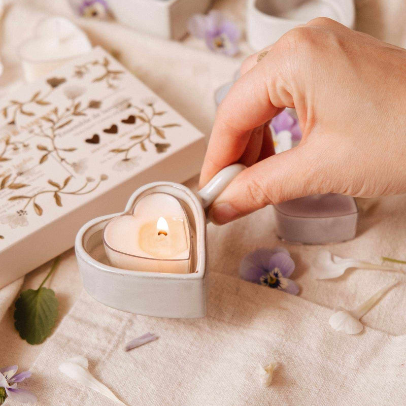Heart-shaped candle being lit on a soft surface with decorative elements